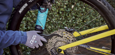 Aandrijflijn van een Cannondale mountainbike die wordt gereinigd met een cassetteklauw en aandrijflijnreiniger.