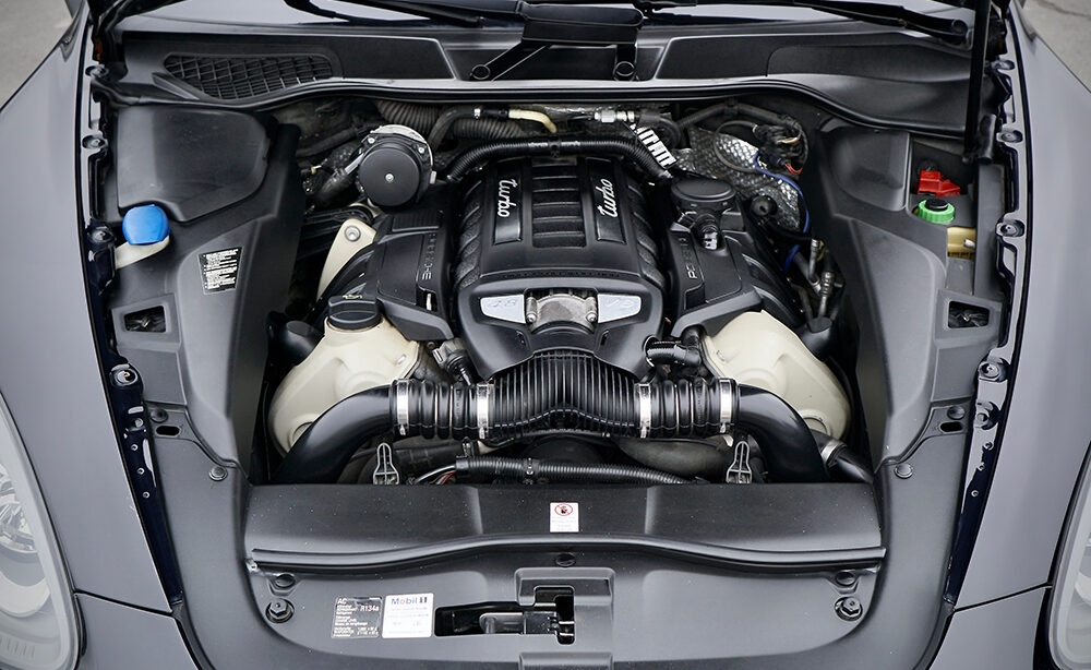 Engine compartment of Porsche Cayenne Turbo V8 with clean components. Open hood top view of auto after preparation for sale. Detailing.