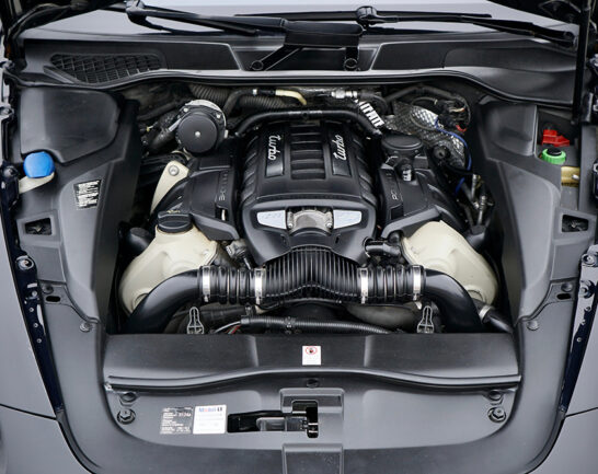Engine compartment of Porsche Cayenne Turbo V8 with clean components. Open hood top view of auto after preparation for sale. Detailing.
