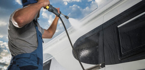 Man spuit camper schoon met hogedrukreiniger.