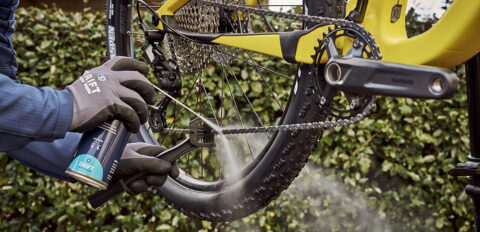 Mountainbike fietsketting die wordt gereinigd/ontvet met een Kettingreiniger in combinatie met een Fietskettingborstel.